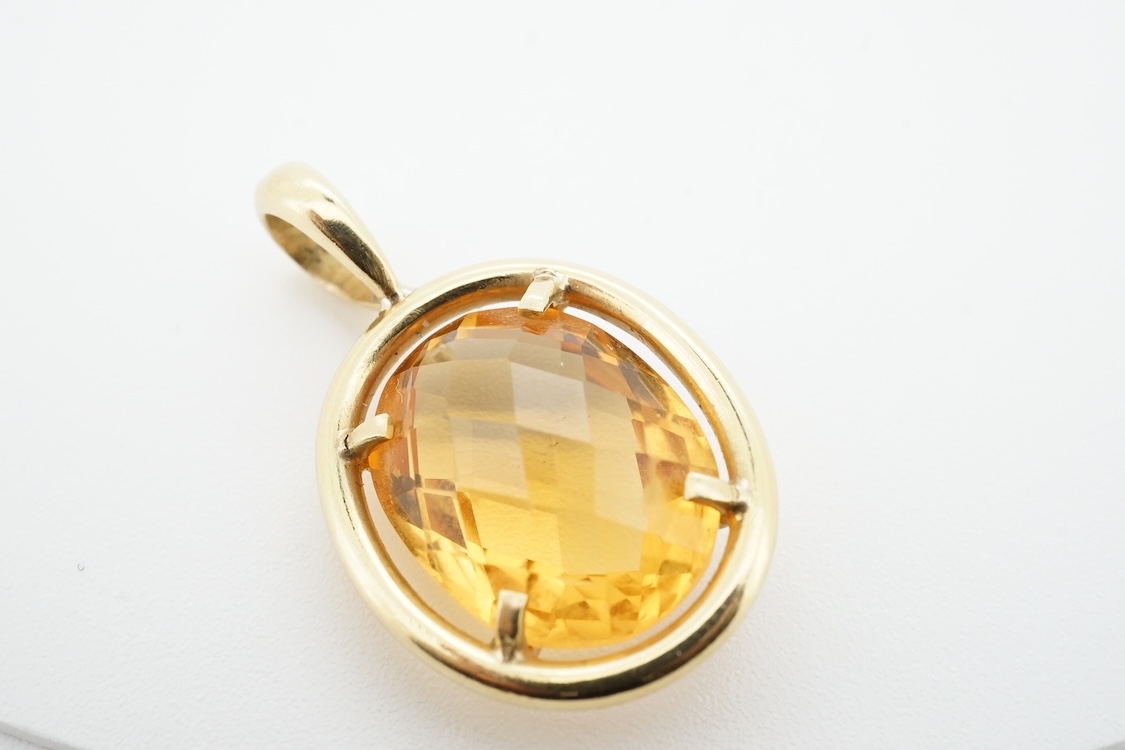 A modern yellow metal (stamped 750) and facet cut oval citrine set pendant, overall 27mm, gross weight 4.9 grams.